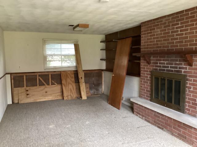unfurnished living room featuring carpet flooring and a brick fireplace