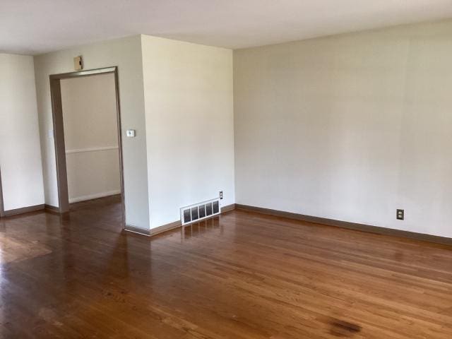 unfurnished room with wood finished floors, baseboards, and visible vents