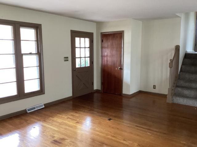 foyer with wood finished floors, baseboards, stairs, and visible vents