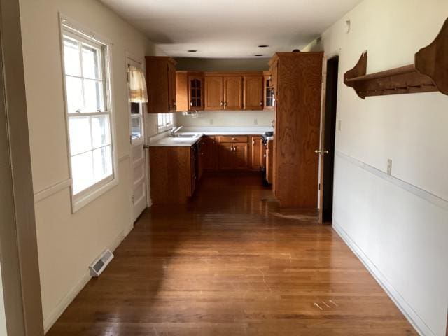 kitchen featuring visible vents, plenty of natural light, glass insert cabinets, and brown cabinets