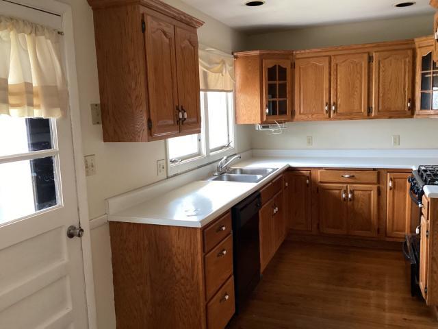 kitchen featuring glass insert cabinets, black appliances, a sink, and brown cabinetry