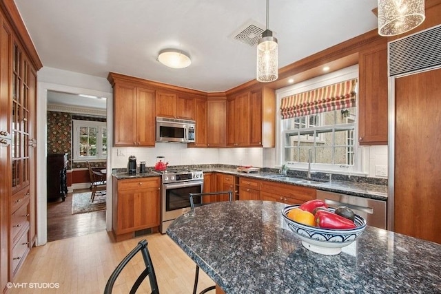 kitchen featuring light wood-style floors, visible vents, brown cabinets, appliances with stainless steel finishes, and a sink