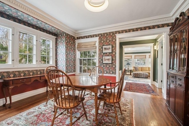 dining room featuring wallpapered walls, wood finished floors, and baseboards