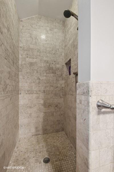 full bath with tiled shower and lofted ceiling