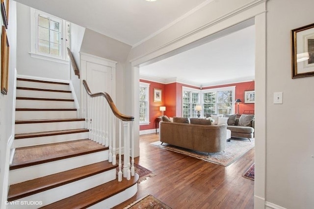 stairway with wood finished floors, baseboards, and ornamental molding