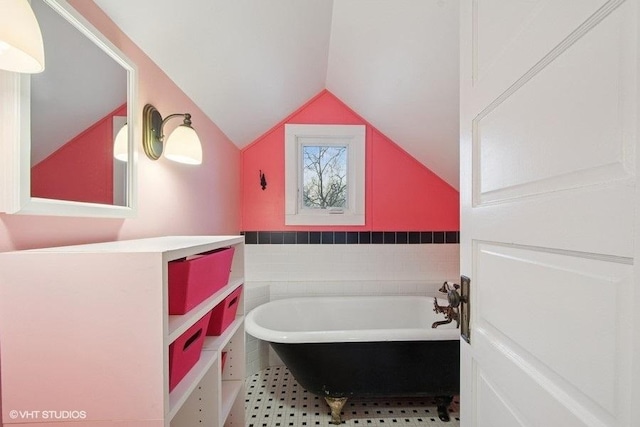 bathroom featuring a soaking tub and lofted ceiling