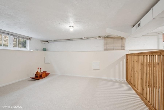 below grade area with a textured ceiling, baseboards, and carpet