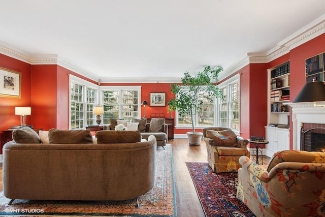 living area with ornamental molding, a brick fireplace, and wood finished floors