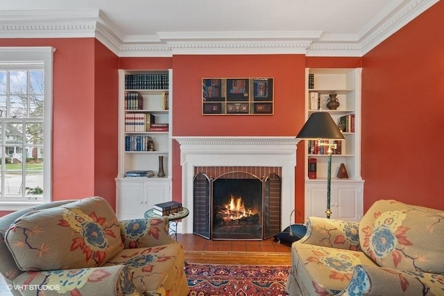 living area with ornamental molding, built in features, and a brick fireplace