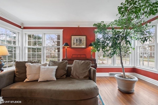 living area with visible vents, baseboards, ornamental molding, and wood finished floors