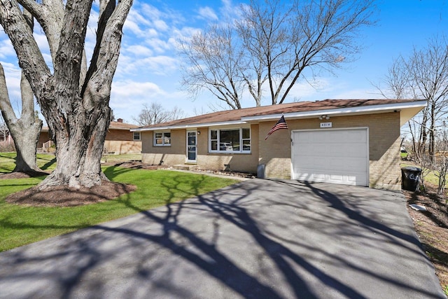 ranch-style home featuring entry steps, a garage, aphalt driveway, brick siding, and a front lawn