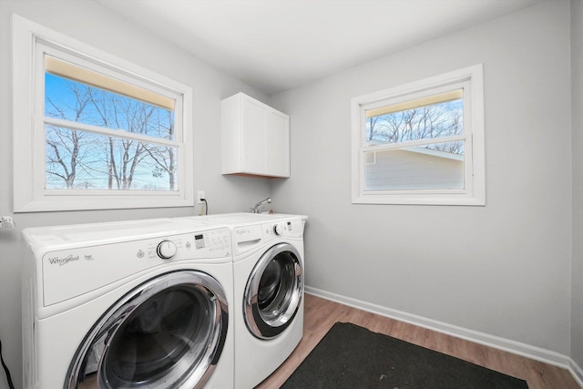 laundry room with light wood-style floors, separate washer and dryer, baseboards, and cabinet space