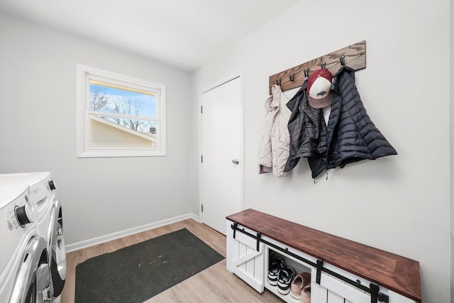 mudroom with light wood-style flooring, baseboards, and washing machine and dryer