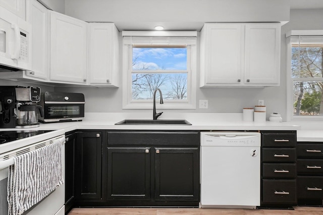 kitchen featuring a sink, white cabinetry, white appliances, and dark cabinets