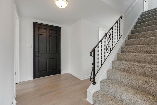 entrance foyer featuring baseboards, wood finished floors, and stairway