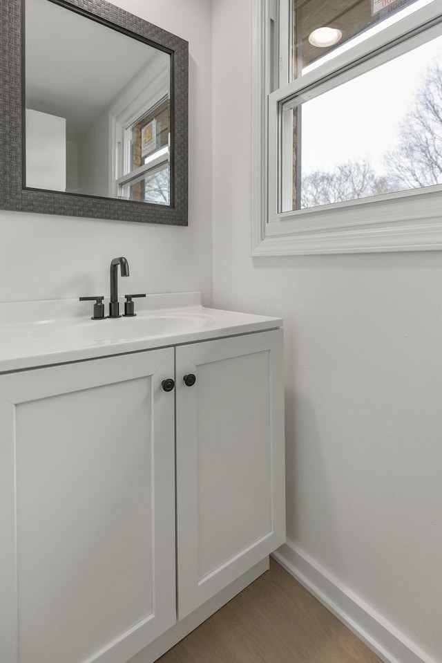 bathroom with baseboards, a wealth of natural light, wood finished floors, and vanity