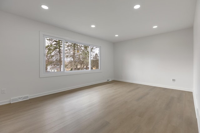 unfurnished room featuring baseboards, visible vents, wood finished floors, and recessed lighting