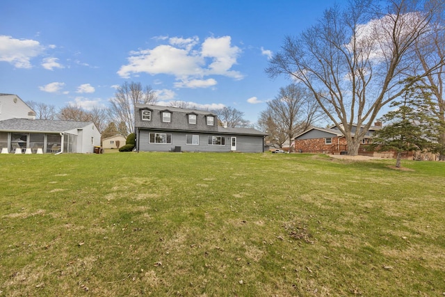 back of property with a sunroom, a shingled roof, and a lawn