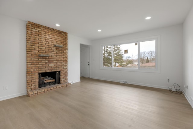 unfurnished living room with recessed lighting, baseboards, a fireplace, and wood finished floors