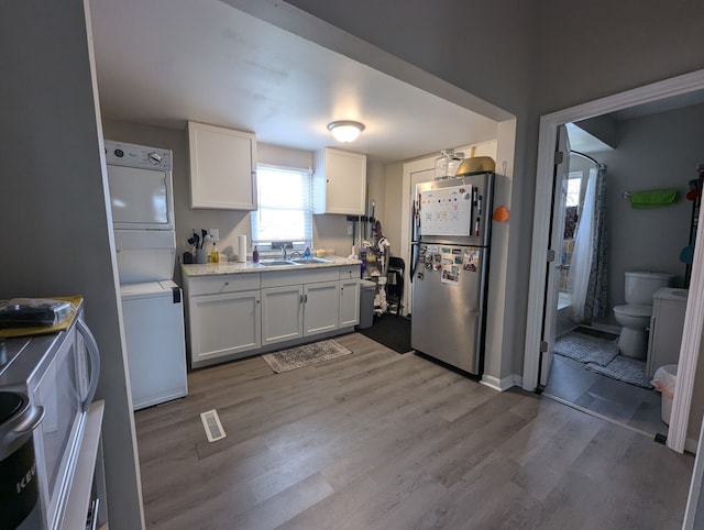 601 S Osborn Ave, Kankakee, IL 60901 - kitchen featuring freestanding refrigerator, stacked washer / drying machine, wood finished floors, white cabinetry, and light countertops