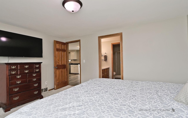 bedroom featuring visible vents, light colored carpet, and ensuite bathroom