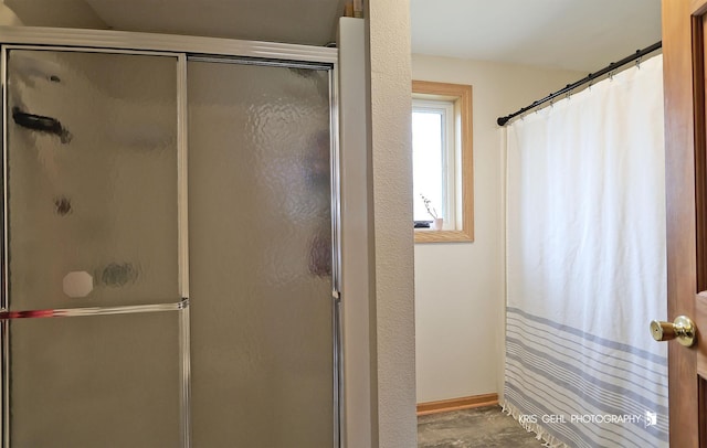bathroom with a shower stall and baseboards