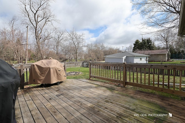 deck featuring grilling area, a detached garage, fence, and a lawn