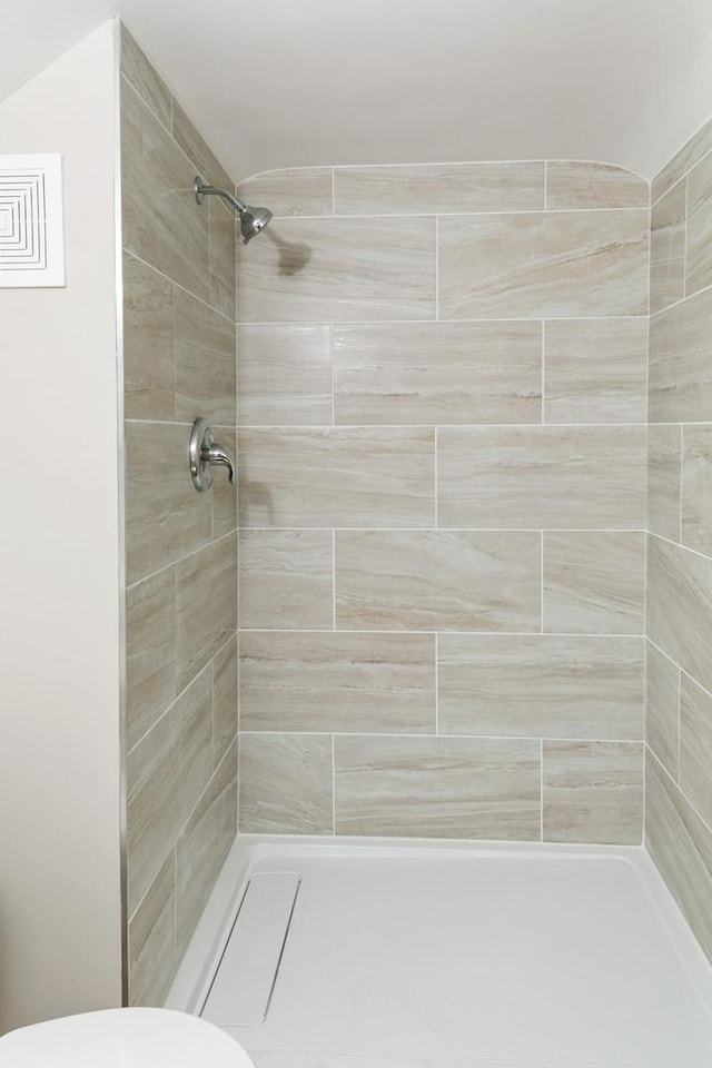 full bathroom featuring toilet and tiled shower
