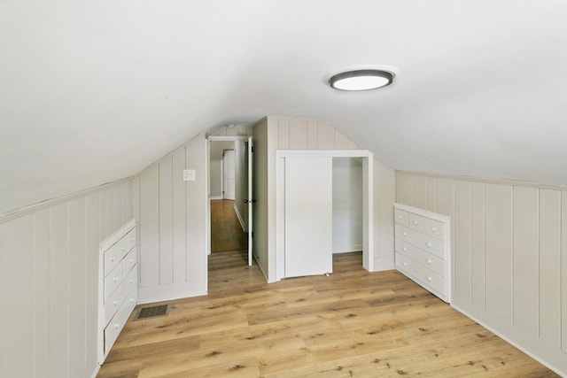 additional living space featuring visible vents, wood finished floors, and lofted ceiling