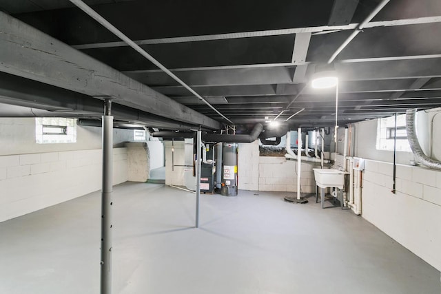 basement with gas water heater, heating unit, and a sink