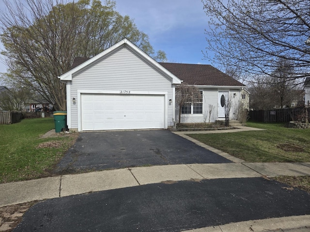 view of front of home with driveway, an attached garage, fence, and a front lawn