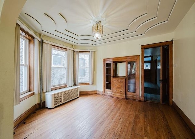 1228 S 59th Ave, Cicero, IL 60804 - spare room featuring baseboards, radiator heating unit, wood finished floors, and a healthy amount of sunlight