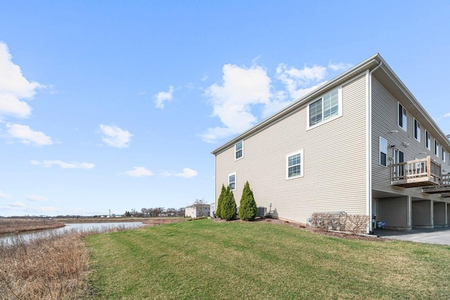 view of home's exterior with a yard, a water view, and central AC