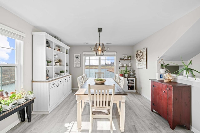 dining area with light wood-style floors, baseboards, and a water view