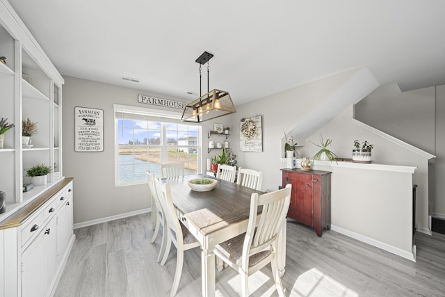 dining area featuring baseboards, light wood-type flooring, and visible vents