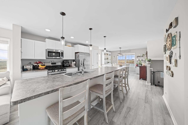 kitchen with stainless steel appliances, a breakfast bar, white cabinetry, and light wood-style floors