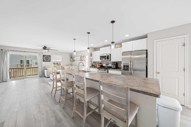 kitchen featuring a sink, appliances with stainless steel finishes, a breakfast bar area, and light wood-type flooring