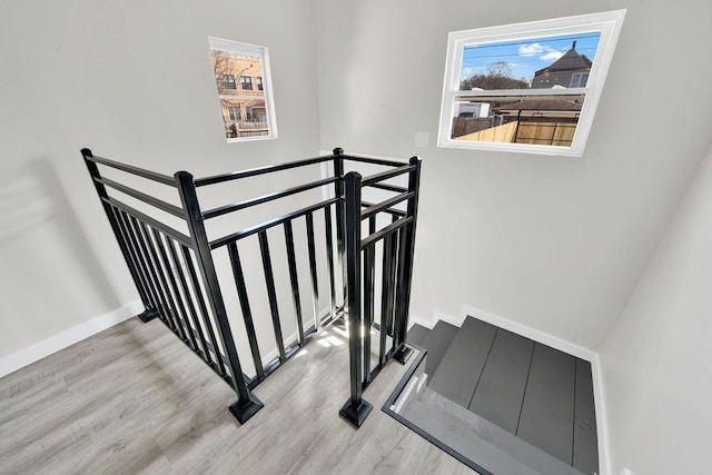 stairs featuring wood finished floors, baseboards, and plenty of natural light