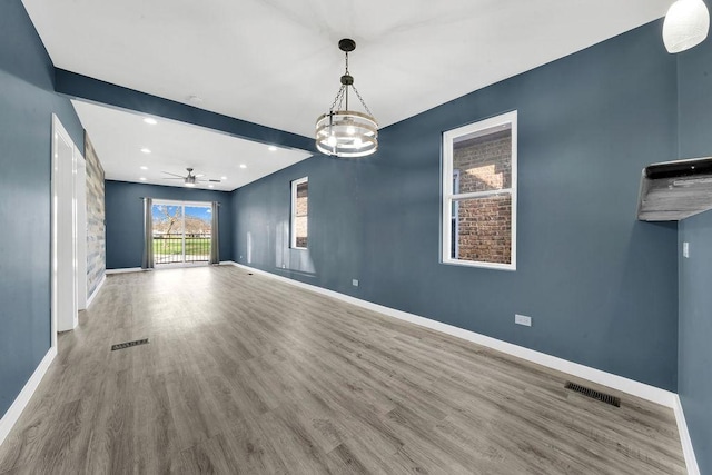 interior space featuring baseboards, visible vents, beam ceiling, ceiling fan with notable chandelier, and wood finished floors