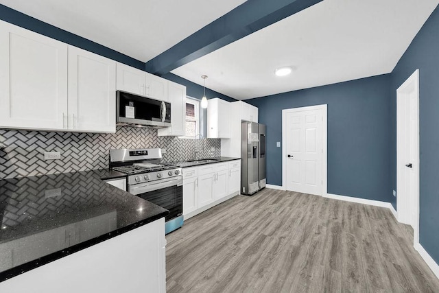 kitchen featuring decorative backsplash, white cabinets, stainless steel appliances, light wood finished floors, and baseboards