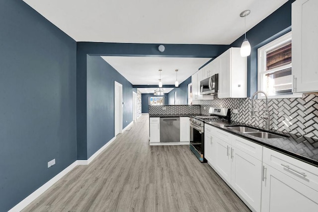 kitchen featuring a sink, appliances with stainless steel finishes, dark countertops, light wood-style floors, and backsplash