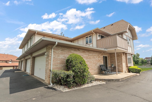 5 Saint Moritz Dr Unit 101, Palos Park, IL 60464 - view of home's exterior featuring a balcony, brick siding, a patio, and asphalt driveway