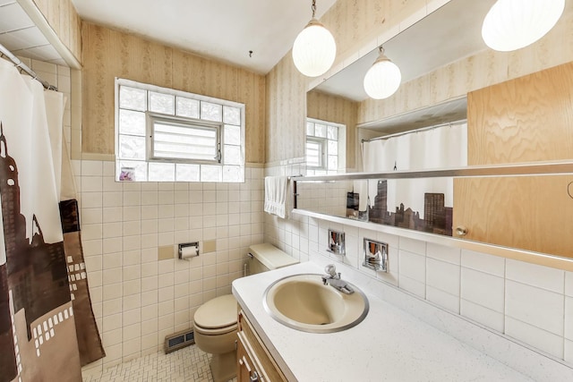 bathroom featuring toilet, wallpapered walls, visible vents, and a wainscoted wall