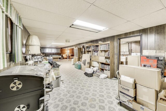 basement with wooden walls, washer / dryer, and a drop ceiling