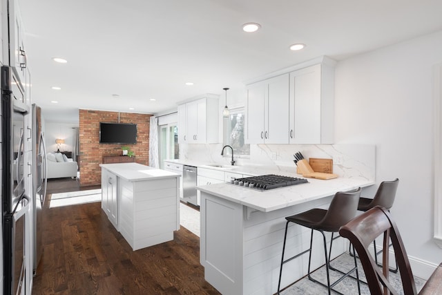69 S Parkway Dr, Naperville, IL 60540 - kitchen with a peninsula, white cabinetry, a sink, dark wood finished floors, and appliances with stainless steel finishes