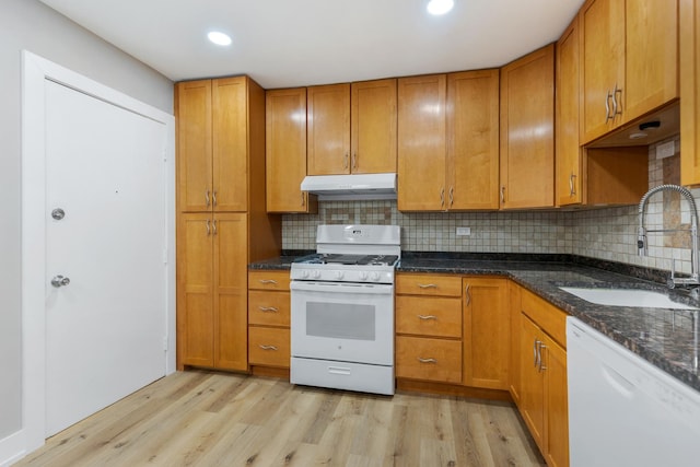 kitchen with a sink, light wood finished floors, brown cabinetry, under cabinet range hood, and white appliances
