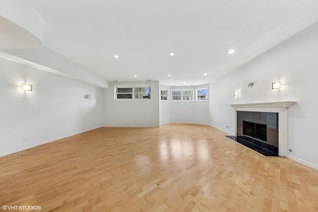 unfurnished living room featuring light wood finished floors, baseboards, a tile fireplace, and recessed lighting