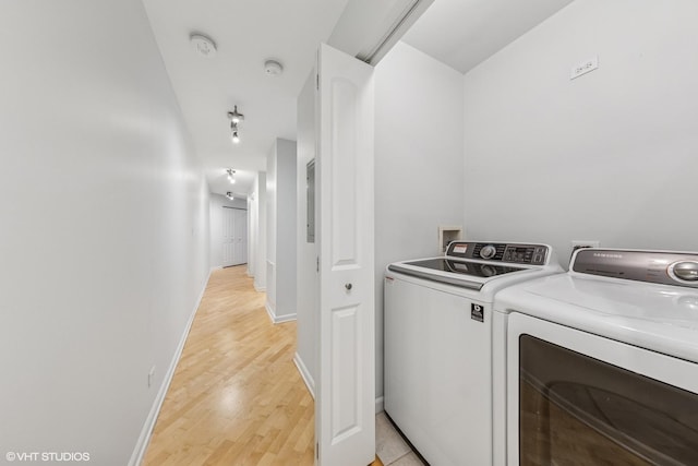 washroom with baseboards, washing machine and dryer, laundry area, and light wood finished floors