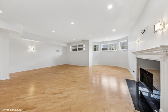 unfurnished living room featuring baseboards, a fireplace, light wood-style flooring, and recessed lighting
