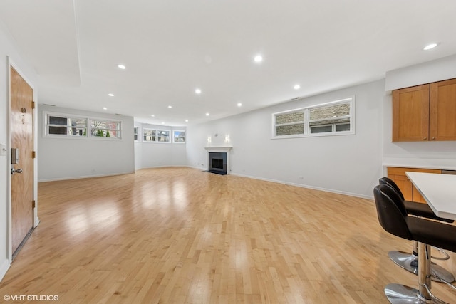 unfurnished living room with baseboards, a fireplace, recessed lighting, and light wood-type flooring